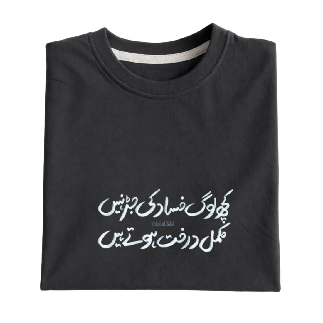 Folded black sweatshirt with white Arabic text on a white background