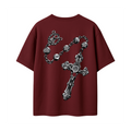 A maroon short-sleeve t-shirt featuring a large, detailed graphic of a silver gothic-style rosary with skull and cross details printed on the front, set against a plain white background.
