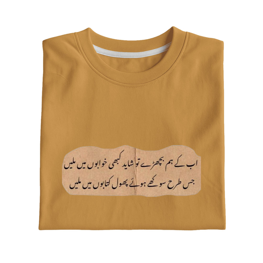 A folded mustard yellow t-shirt with a printed beige graphic containing black Urdu calligraphy, displayed on a solid white background.