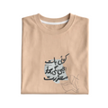 Folded beige t-shirt with Arabic text design on a light gray background