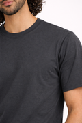 Man wearing a plain black t-shirt against a white background