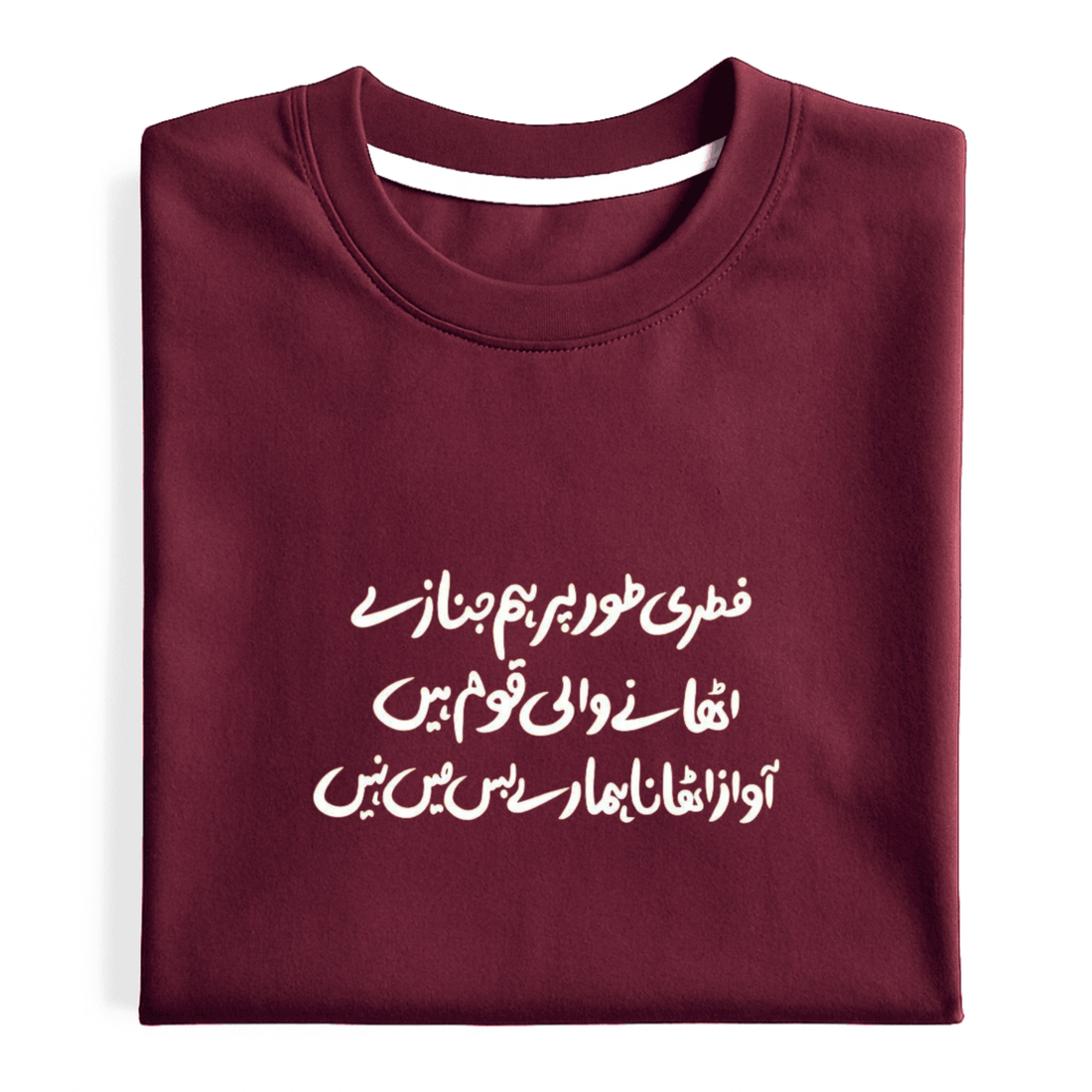 A folded maroon crewneck t-shirt with white Urdu text printed on the front, displayed against a clean white background.